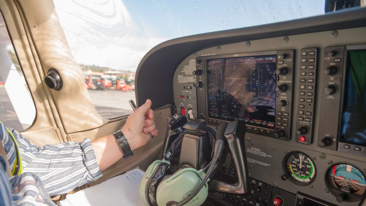 A pilot working the avionics stack in the cockpit of a light aircraft